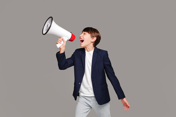 Fashionable teenager boy screaming through megaphone in studio. A lot of copy space