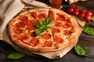 Pepperoni pizza with basil on a wooden background