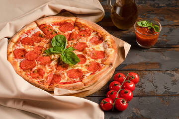 Pepperoni pizza on a wooden background with basil