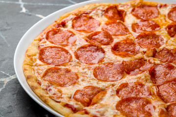 Pepperoni pizza on dark marble table close up