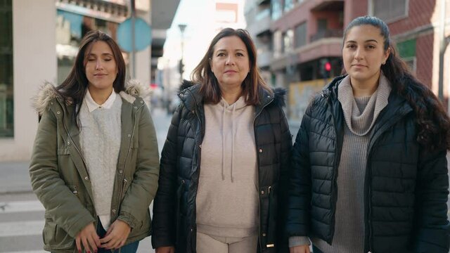 Mother and daughters smiling confident standing with arms crossed gesture at street