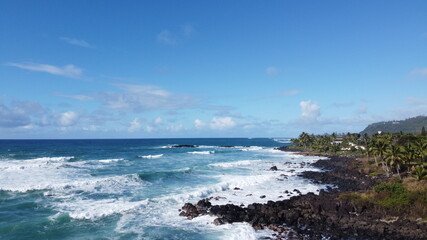 Fototapeta na wymiar Oceanview coastline waves crashing into rocks blue clear skies landscape view drone in Hawaii