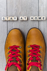 Stay home - lettering from cubes with letters. Legs in track boots on the gray floor.