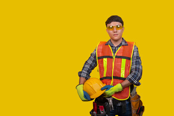 Young man with construction safety equipment on yellow isolated background, concept of safety at work
