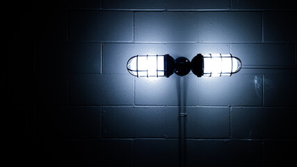 Dark creepy basement bunker concrete block wall and glowing old lamp light background copy space