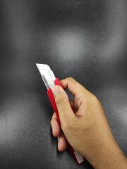 Photo of a hand holding a cutter knife isolated on black background, Not Focus