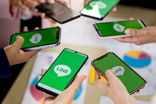 Bangkok/Thailand - August 06, 2021: People hold smartphones in different brands and various operating systems with logos of Line app, one of most popular messege applications