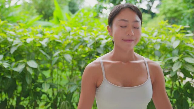 Young woman doing meditation exercise stretching sports, white tank top and yellow Legging, Female practicing yoga, natural balance between body and mental development. With bautiful green garden.