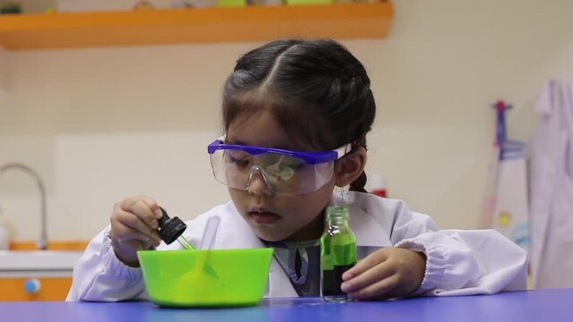 Asian kid push chemicals on trays in science lab in school to create experience as a future scientist