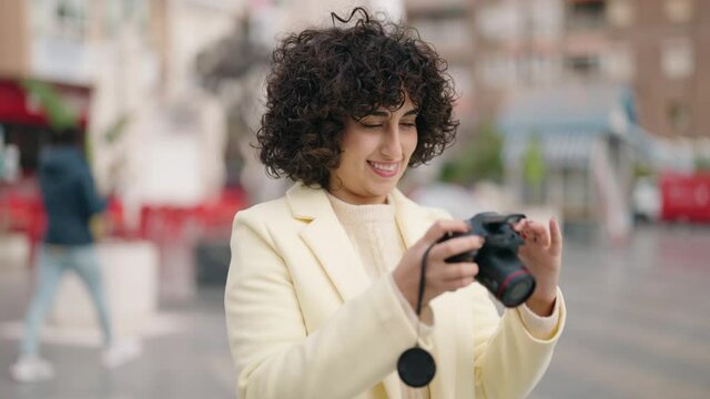 Young woman smiling confident using professional camera at street