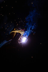 Close-up of a welder working in a workshop. Shallow depth of field. Welding of metal structures. Semi-automatic manual welding. MIG welding.