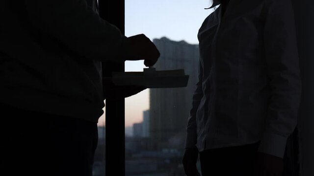 Silhouette of two people plotting to collude with each other