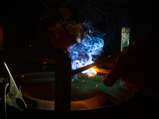 Close-up of a welder working in a workshop. Shallow depth of field. Welding of metal structures. Semi-automatic manual welding. MIG welding.