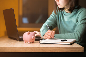 The girl puts her savings in a piggy bank.