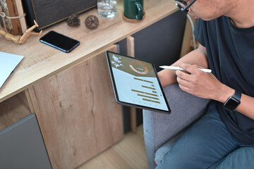 Young man analyzing financial graph on digital tablet.