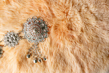 Fashion accessory handmade silver metal buckle placed on orange fur cloth background.