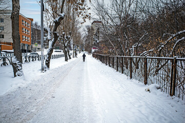 Naklejka premium A man walks on a snow-covered sidewalk on a winter day