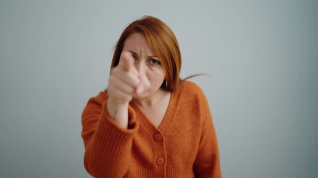 Young redhead woman furious pointing with finger over isolated withe background