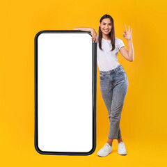 Woman showing white empty smartphone screen and ok sign