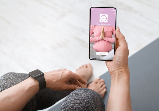 Young wonan using mobile application for yoga during pregnancy