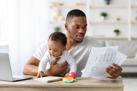 Stressed Black Father With Little Baby Trying To Work At Home Office