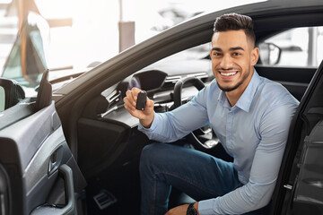 Handsome arab man customer sitting in auto and holding key