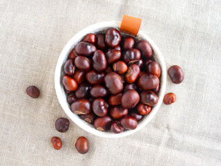 Raw chestnuts in a textile basket, top view