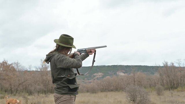 Hunter woman with shotgun hunting in the field.