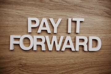 Pay It Forward alphabet letters on wooden background