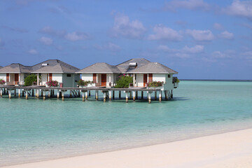 Morning in the Maldives, Indian Ocean shore with white sand, corals and villas over azure water