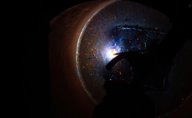 Close-up of a welder working in a workshop. Welding inside a metal structure.