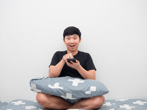 Man using mobile phone on the bed looking at cemera