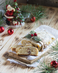 Christmass stollen cake with nuts, raisins and dried fruit on cutting board on wooden background, selective focus
