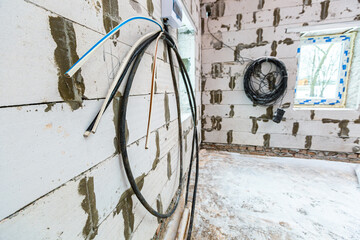 Image with focus view on the electrical power cables fixed on the wall made from foamed concrete...