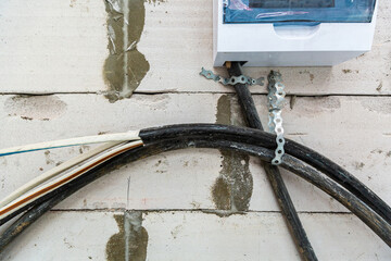 Image with focus view on the electrical power cables fixed on the wall made from foamed concrete...