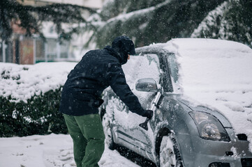 Middle aged man cleaning car from snow and ice
