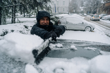 Middle aged man cleaning car from snow and ice