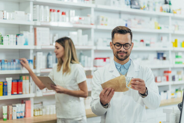 Fototapeta na wymiar Male pharmacist packing drugs in a paper bag while working at a pharmacy
