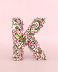 Creative letter K concept made of fresh Spring wedding flowers. Flower font concept on pastel pink background..