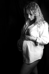 Naklejka premium Black and white photoshoot of a pregnant woman in the studio