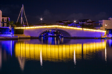Illuminated bridge with lights reflection in water of sea bay at night