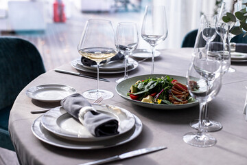 Fototapeta premium tuna salad on the serving table with wine glasses and flowers. grey tablewear. selective focus