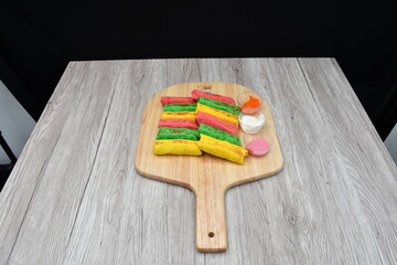 Colorful shawarmas kept on a wooden table against a plain black background