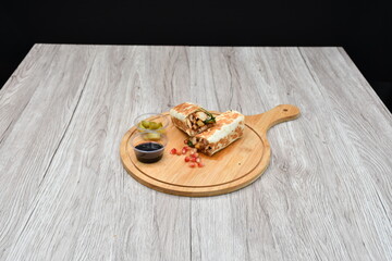 Shawarma kept on a wooden table against a plain black background