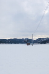 Fototapeta na wymiar In Shiga Prefecture, Japan, in the middle of winter, a landscape of snow-covered plains and a small hut standing there.