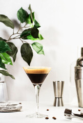 Espresso martini alcoholic cocktail with vodka, coffee liqueur, syrup and ice, white background, bar tools, copy space