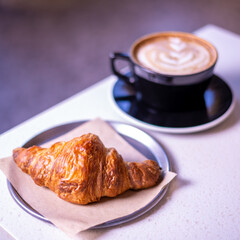 Hot coffee and croissants on a marble table.