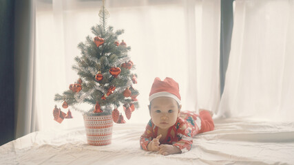 Obraz na płótnie Canvas Cute little baby in Santa hat near Christmas tree.