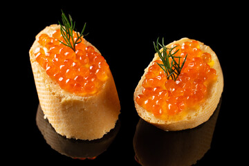 Slices of bread with red caviar on dark background.