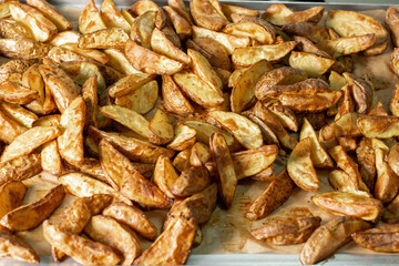 Selective focus. Baking tray with baked potatoes, fragrant rustic potatoes.